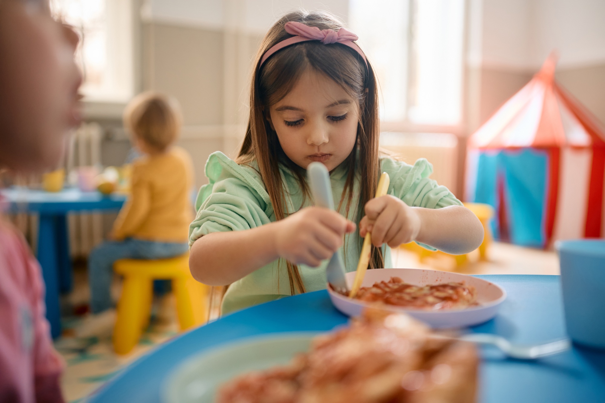 Little girl eating lunch at kindergarten.